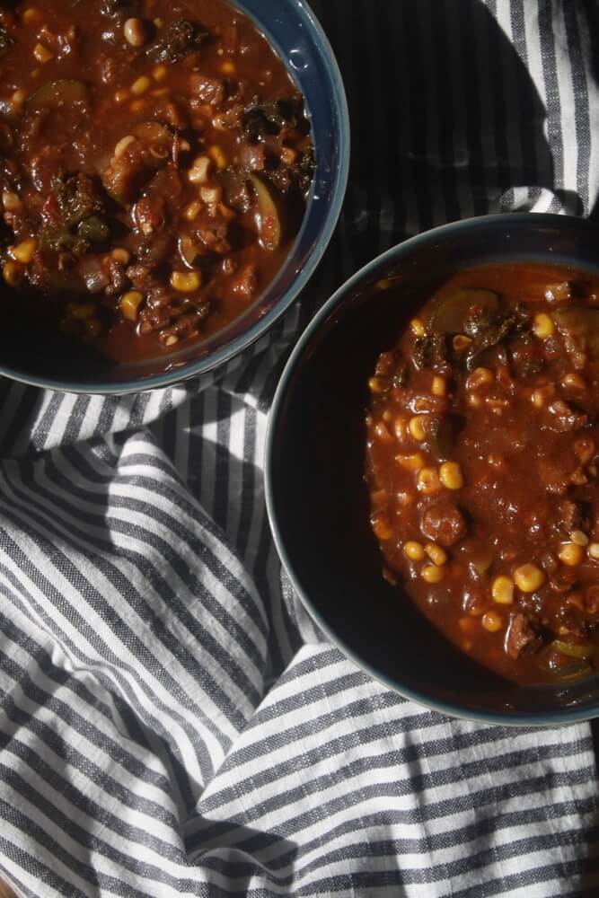 beef vegetable stew in two blue bowls on striped towel