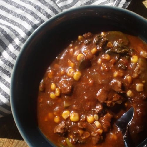 beef vegetable stew in blue bowl with spoon