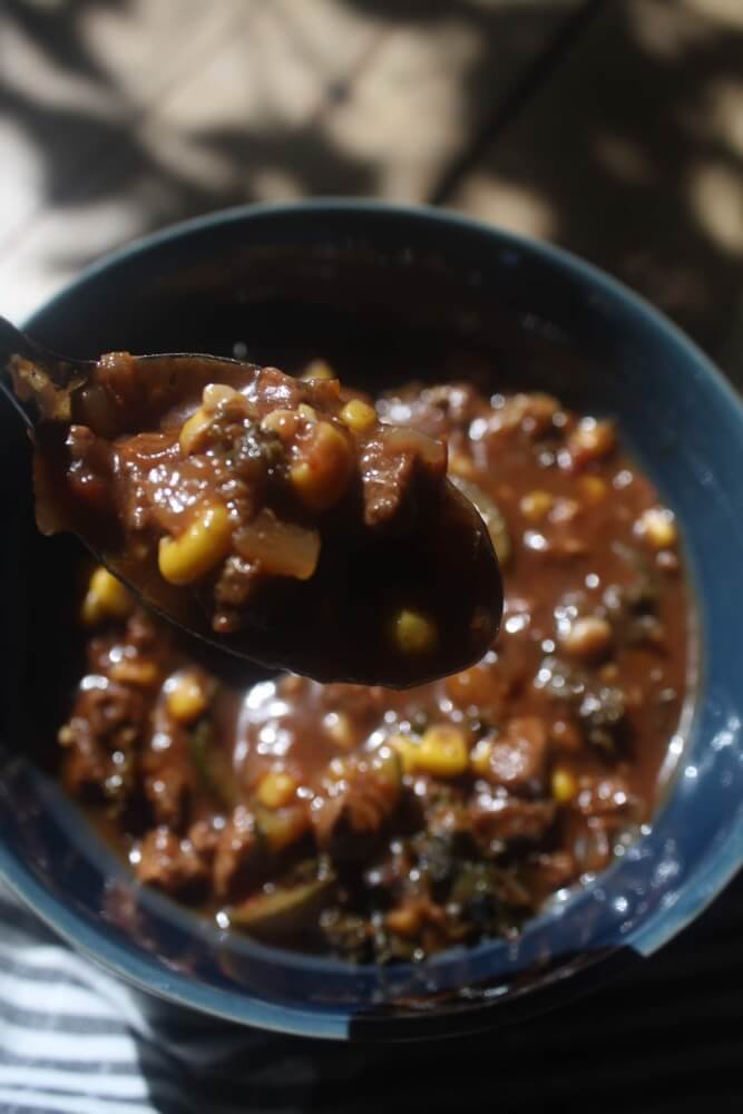 spoonful of stew with blue bowl in background