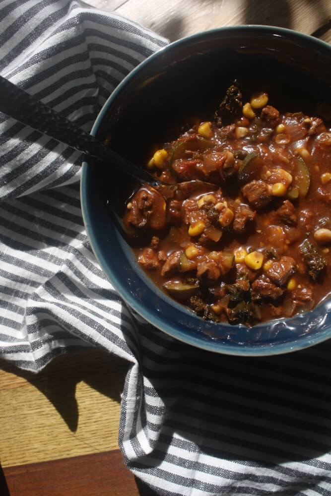 overhead view of blue bowl and spoon with beef vegetable stew